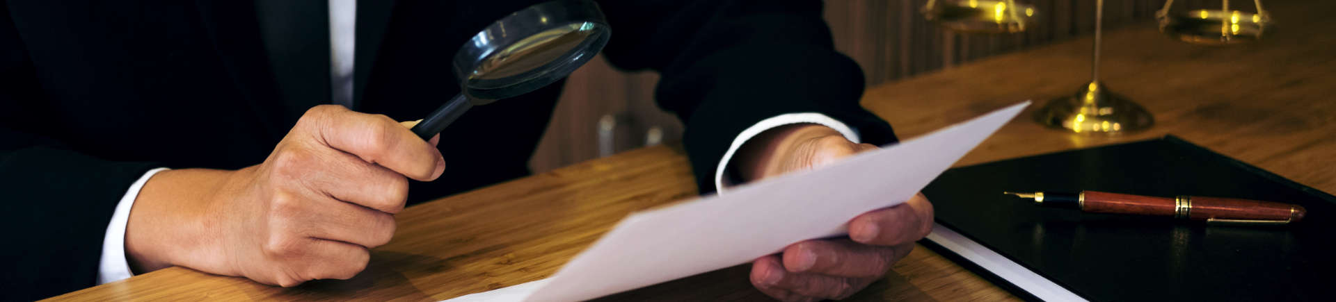 attorney at the desk in his office checking a document with a magnifying glass
